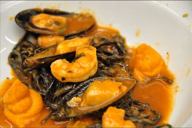 Sphaguetti al nero di seppia con salsa marinera y frutos del mar, emulsión de boniato y polvo de pistacho.