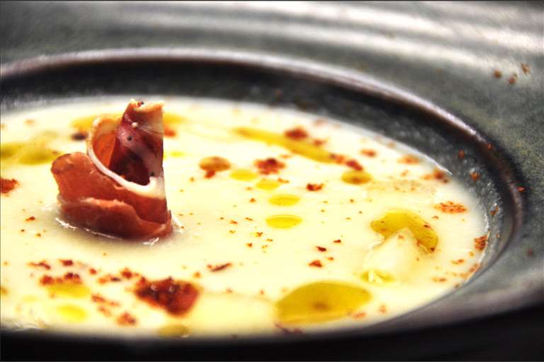 Sopa fría de ajoblanco, melón y aceite de albahaca, con jamón de Teruel.
