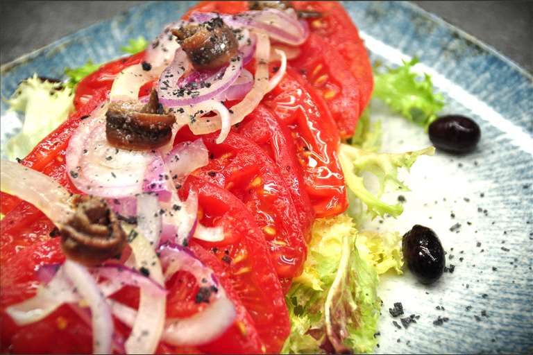 Ensalada de Tomate Rosa de Barbastro, cebolla roja, olivas de Aragón y anchoas, con su aliño tradicional AOVE.