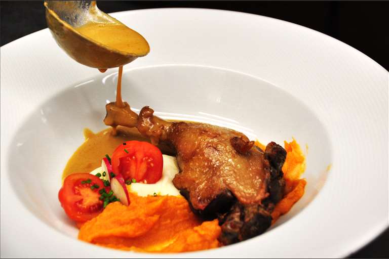 Muslo de pato confitado con salsa de naranja y parmentier.
