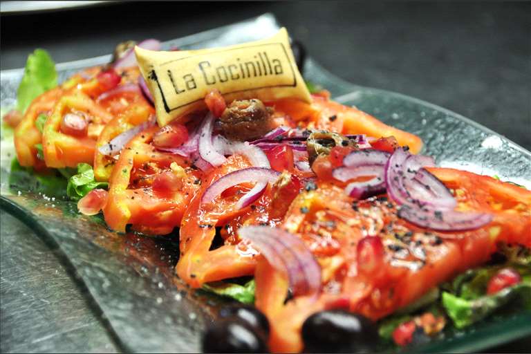 Ensalada de Tomate Rosa de Barbastro, cebolla roja, olivas de Aragón y anchoas, con su aliño tradicional AOVE.