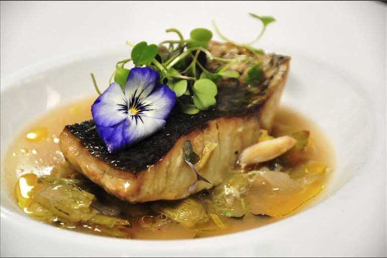 Corvina al horno, cama de borraja y alcahofas, y leche de tigre templada.