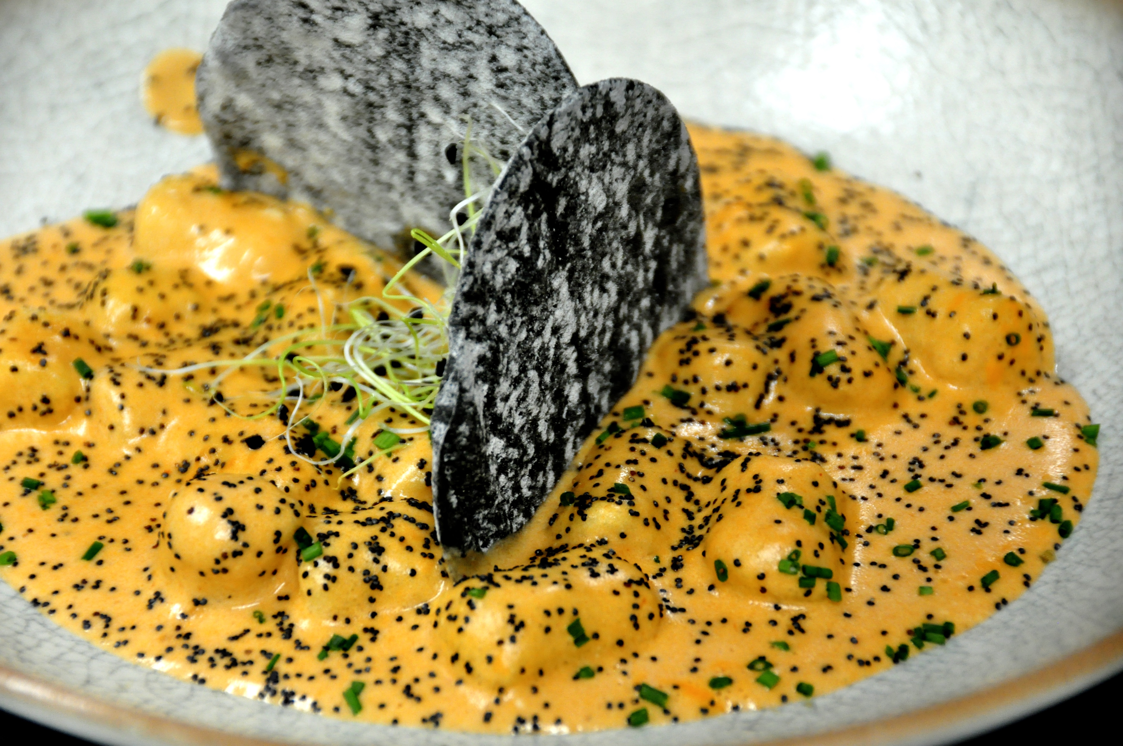 Ñoqui de patata y semillas de amapola, con salsa Aurora, parmesano y crujiente de pan negro.